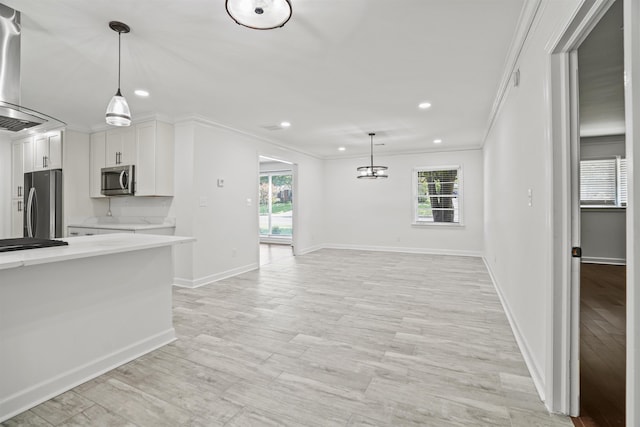 kitchen featuring stainless steel appliances, white cabinetry, ornamental molding, and pendant lighting