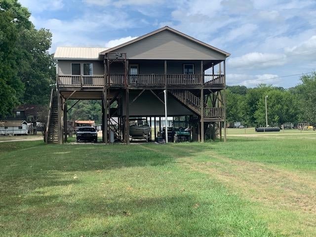 back of property with a carport and a yard