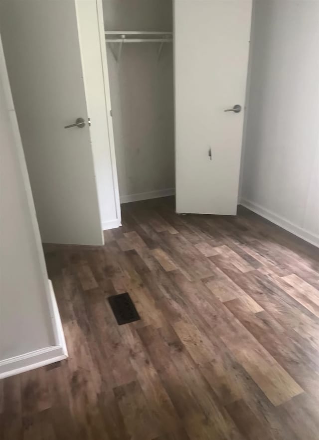 unfurnished bedroom featuring dark hardwood / wood-style floors and a closet