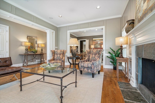 living room with wood-type flooring, crown molding, a premium fireplace, and ornate columns