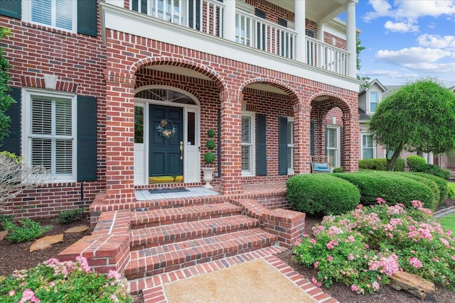 view of exterior entry with a balcony