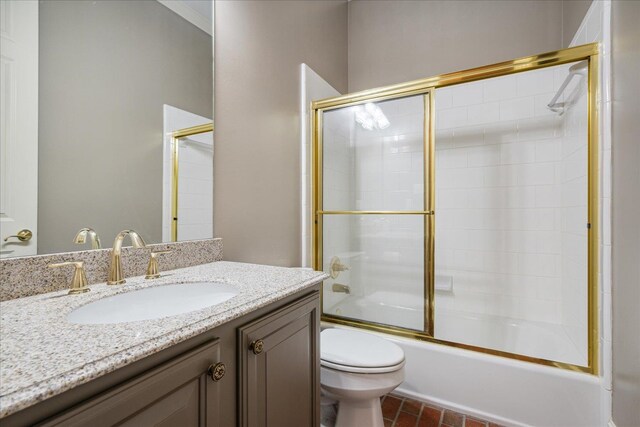 full bathroom featuring vanity, combined bath / shower with glass door, and toilet