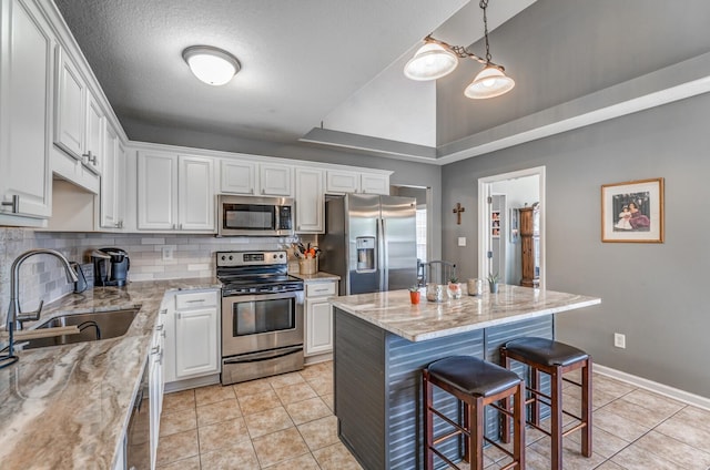 kitchen featuring light stone counters, white cabinetry, stainless steel appliances, and a center island