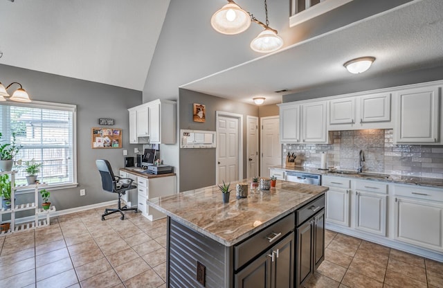 kitchen featuring sink, white cabinetry, a kitchen island, tasteful backsplash, and light tile patterned flooring