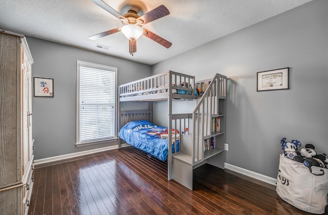 bedroom featuring ceiling fan, dark wood-type flooring, and a textured ceiling