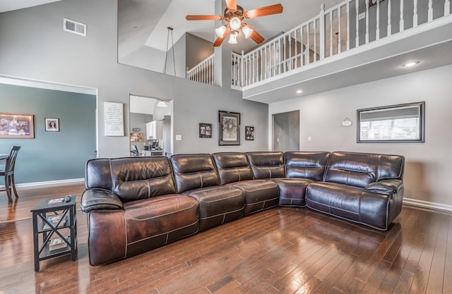 living room featuring a towering ceiling, wood-type flooring, and ceiling fan