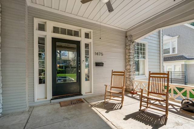 view of exterior entry with ceiling fan and a porch