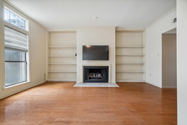 unfurnished living room featuring built in features, crown molding, and wood-type flooring