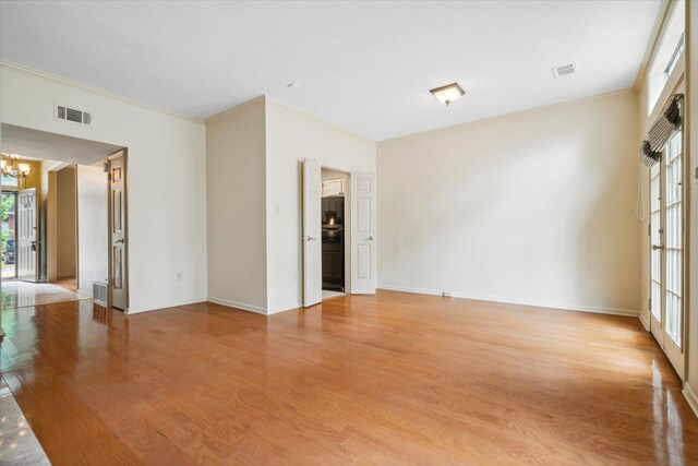 unfurnished room with light wood-type flooring, a chandelier, and ornamental molding