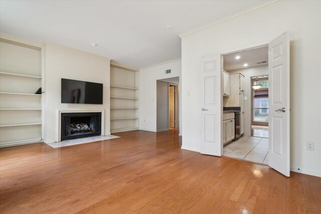 unfurnished living room with crown molding, built in features, and light hardwood / wood-style floors