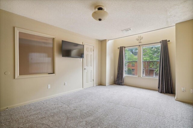 unfurnished bedroom with connected bathroom, a textured ceiling, and light carpet