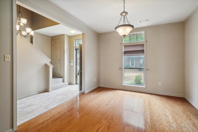 spare room with ornamental molding, a healthy amount of sunlight, and light hardwood / wood-style floors