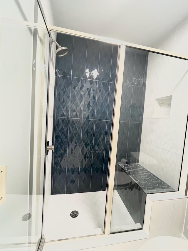 bathroom featuring a shower with shower door and toilet