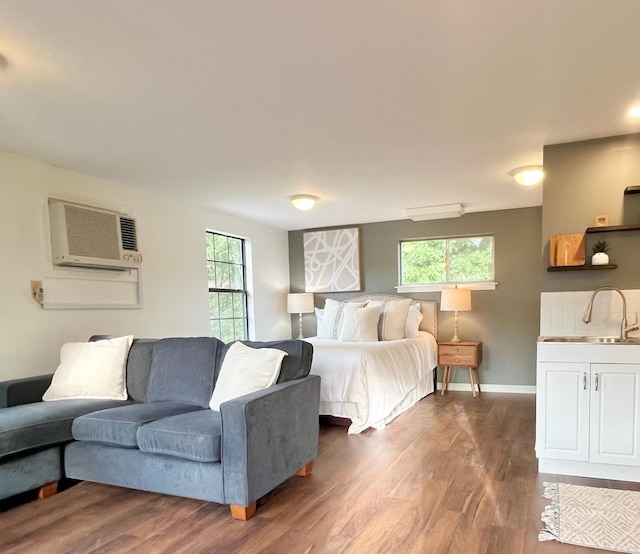 bedroom featuring dark hardwood / wood-style flooring, sink, and an AC wall unit