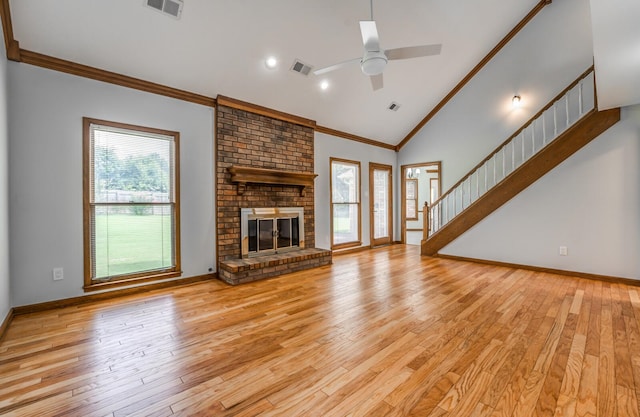 unfurnished living room with light wood-type flooring, a brick fireplace, brick wall, ceiling fan, and ornamental molding