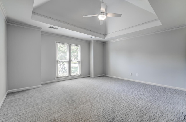 empty room with a raised ceiling, carpet, ornamental molding, and ceiling fan