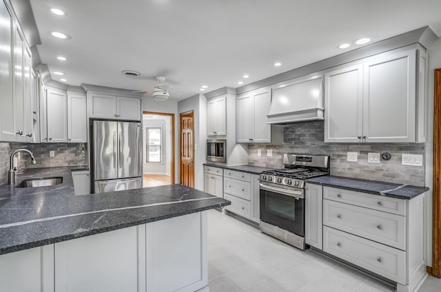 kitchen featuring stainless steel appliances, custom exhaust hood, tasteful backsplash, and ceiling fan