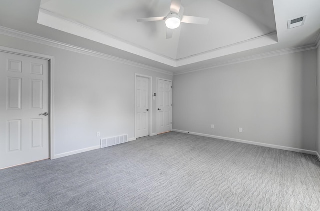 unfurnished bedroom with a tray ceiling, carpet floors, crown molding, and ceiling fan