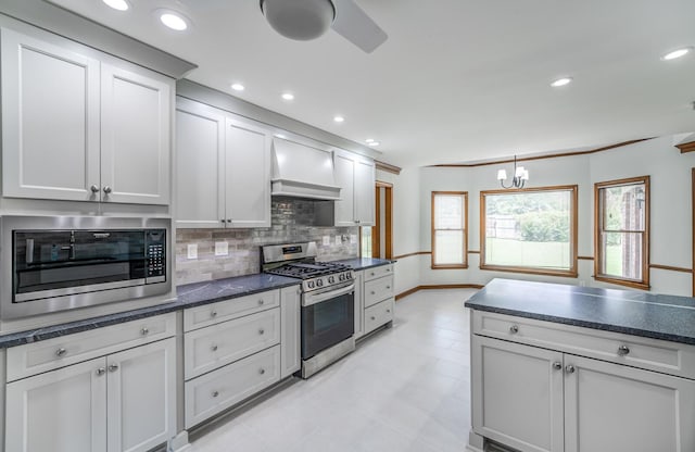 kitchen with custom range hood, light tile patterned floors, an inviting chandelier, appliances with stainless steel finishes, and decorative backsplash