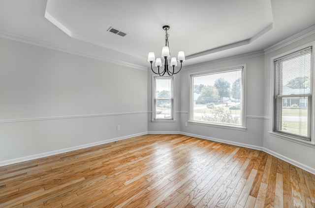 spare room featuring light hardwood / wood-style floors, a notable chandelier, crown molding, and a tray ceiling