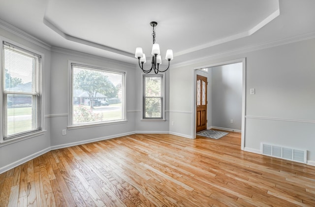 unfurnished room featuring a notable chandelier, light hardwood / wood-style flooring, and a tray ceiling