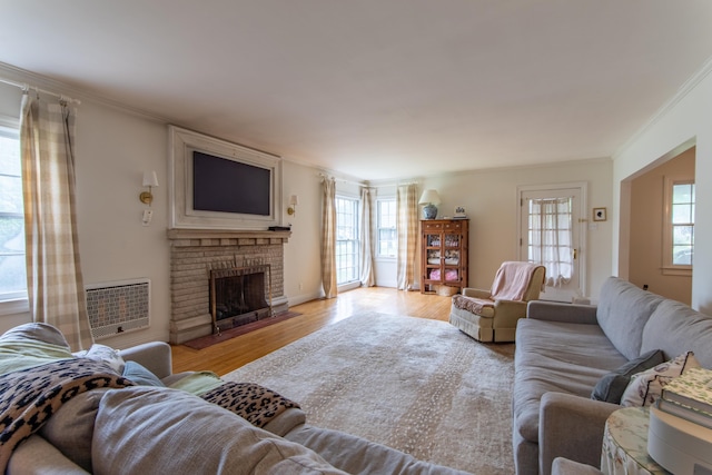 living room with a brick fireplace, light wood-type flooring, and ornamental molding