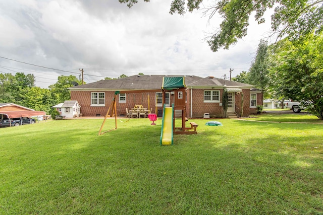 back of property featuring a playground, a lawn, and a carport