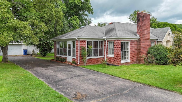 view of front of property featuring a garage, a sunroom, and a front yard