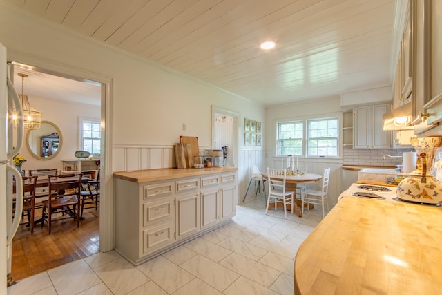 kitchen featuring butcher block countertops, pendant lighting, plenty of natural light, and light tile patterned floors