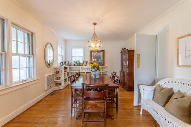 dining area featuring crown molding, light wood-type flooring, and a chandelier