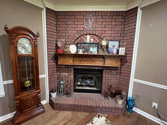 living room with hardwood / wood-style flooring, a brick fireplace, and ornamental molding