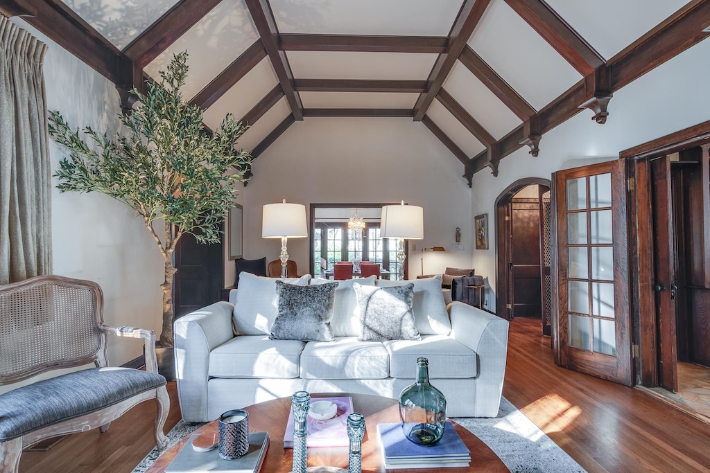 living room with wood-type flooring, high vaulted ceiling, and beamed ceiling