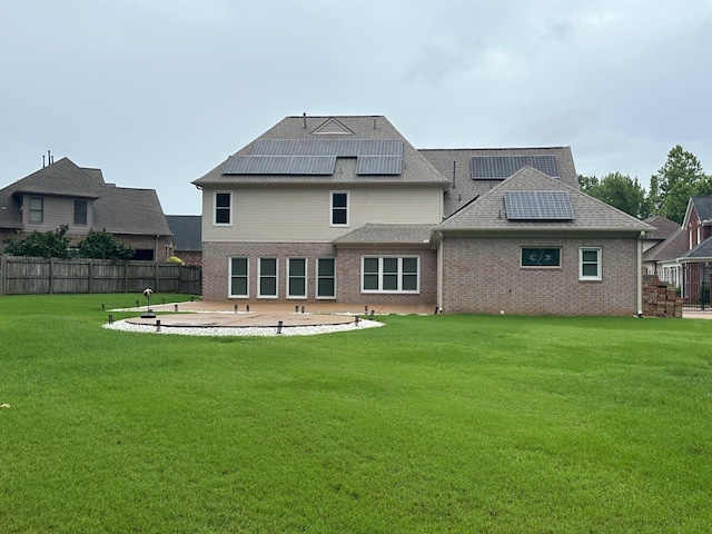 rear view of property with a lawn, a patio area, and solar panels