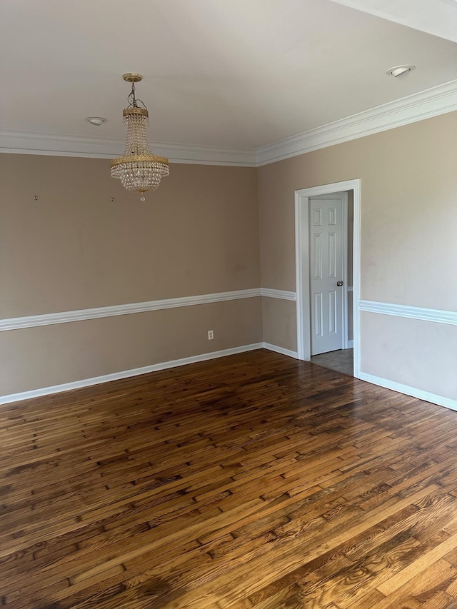 unfurnished room with ornamental molding, dark wood-type flooring, and an inviting chandelier