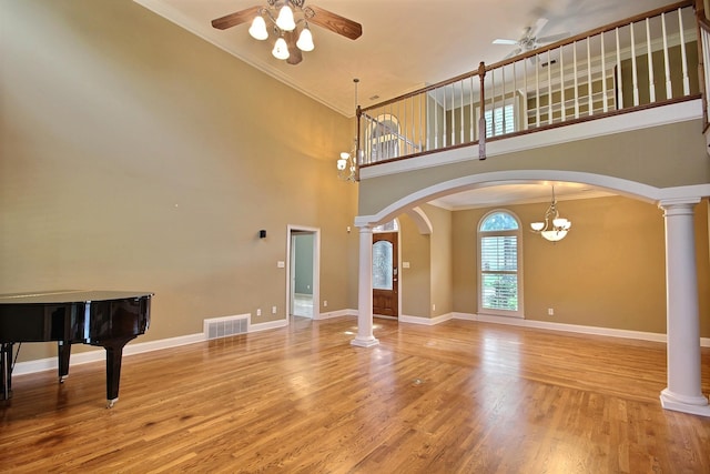 unfurnished living room featuring hardwood / wood-style flooring, ceiling fan, and ornate columns