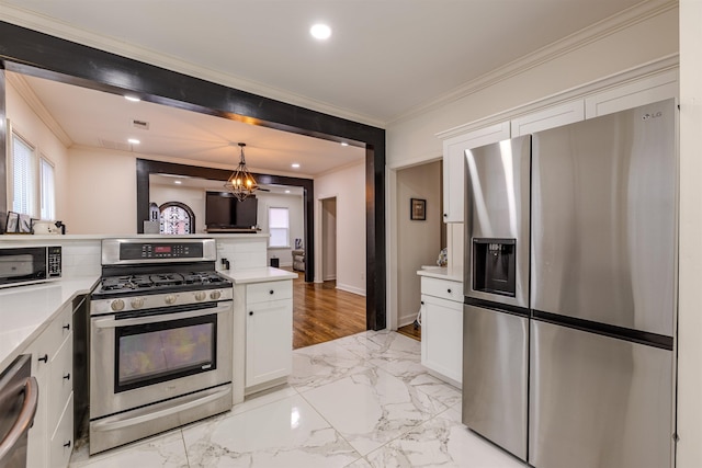 kitchen featuring stainless steel appliances, crown molding, white cabinets, and decorative light fixtures