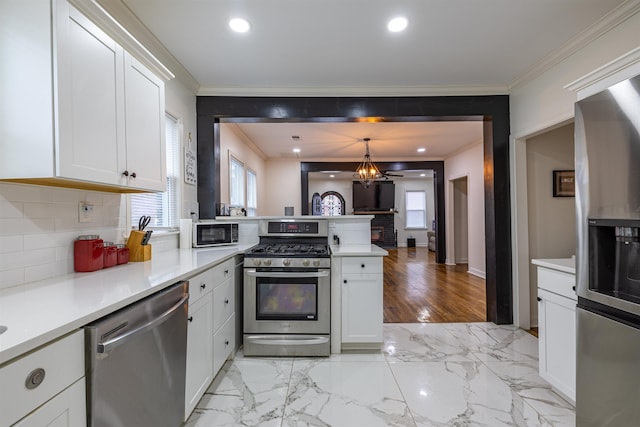 kitchen featuring stainless steel appliances, white cabinetry, pendant lighting, and crown molding