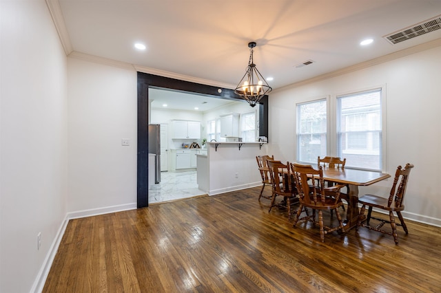 dining area with ornamental molding, hardwood / wood-style floors, and an inviting chandelier