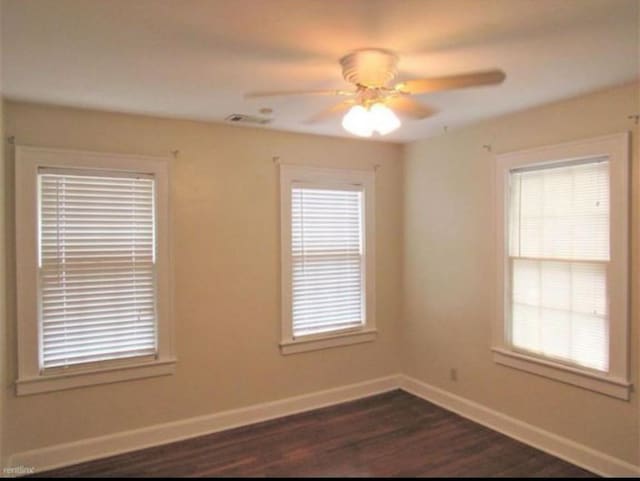 unfurnished room featuring plenty of natural light, dark hardwood / wood-style floors, and ceiling fan