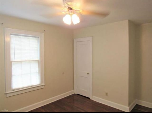 unfurnished room with a healthy amount of sunlight, ceiling fan, and dark wood-type flooring