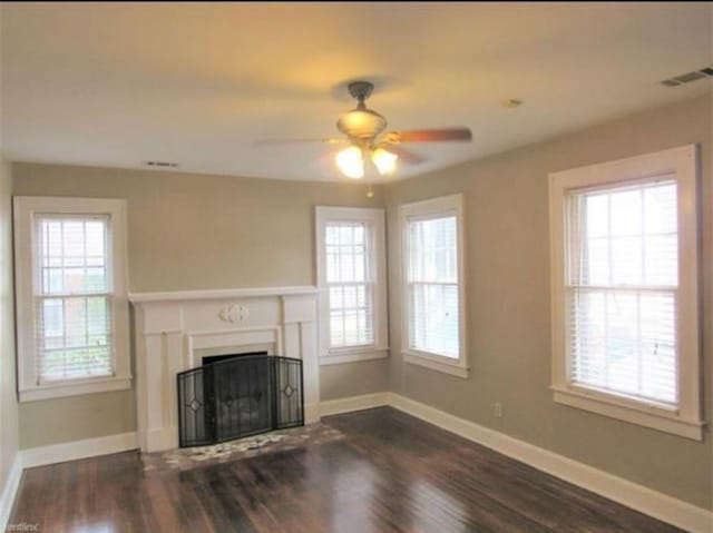 unfurnished living room featuring plenty of natural light, dark wood-type flooring, and ceiling fan