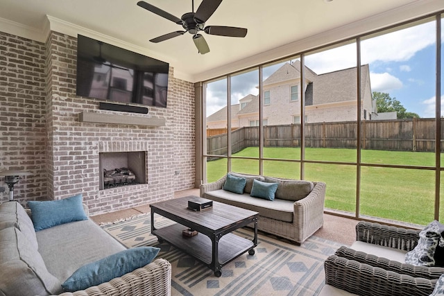 sunroom / solarium with a healthy amount of sunlight, a brick fireplace, and ceiling fan