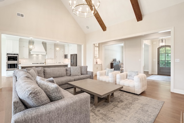 living room with high vaulted ceiling, a notable chandelier, light hardwood / wood-style floors, and beam ceiling