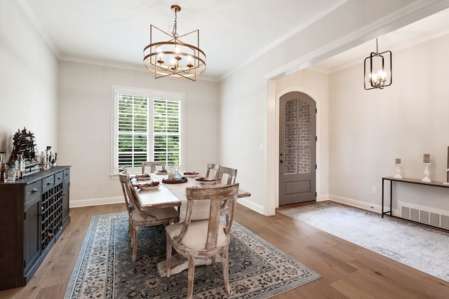 dining area featuring wood-type flooring, crown molding, and a chandelier