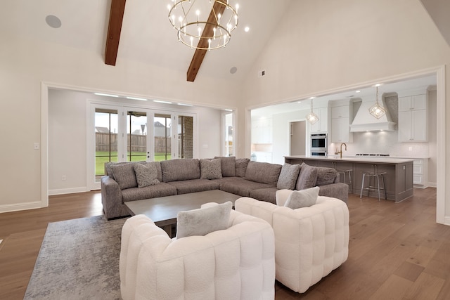 living room featuring beamed ceiling, light hardwood / wood-style flooring, an inviting chandelier, and high vaulted ceiling