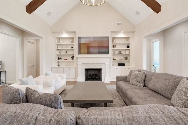 living room featuring light hardwood / wood-style floors, a fireplace, beam ceiling, and high vaulted ceiling