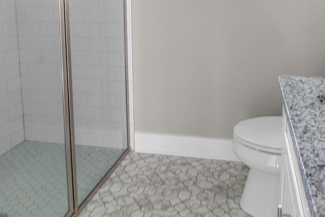 bathroom featuring vanity, a tile shower, tile patterned floors, and toilet