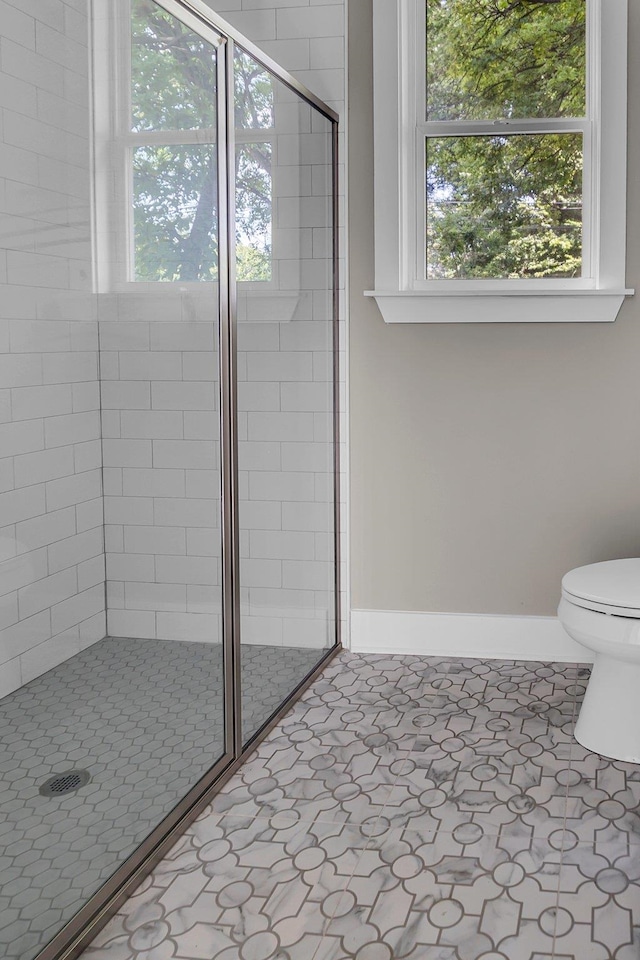 bathroom with a shower with door, tile patterned floors, and toilet