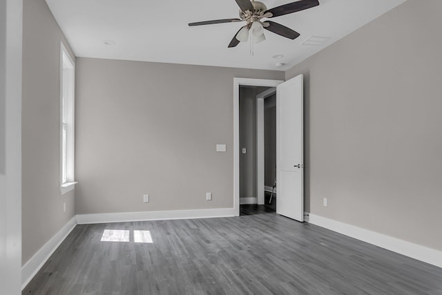 empty room featuring ceiling fan, plenty of natural light, and dark hardwood / wood-style flooring