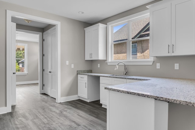 kitchen featuring white cabinetry, sink, light stone counters, and light hardwood / wood-style flooring